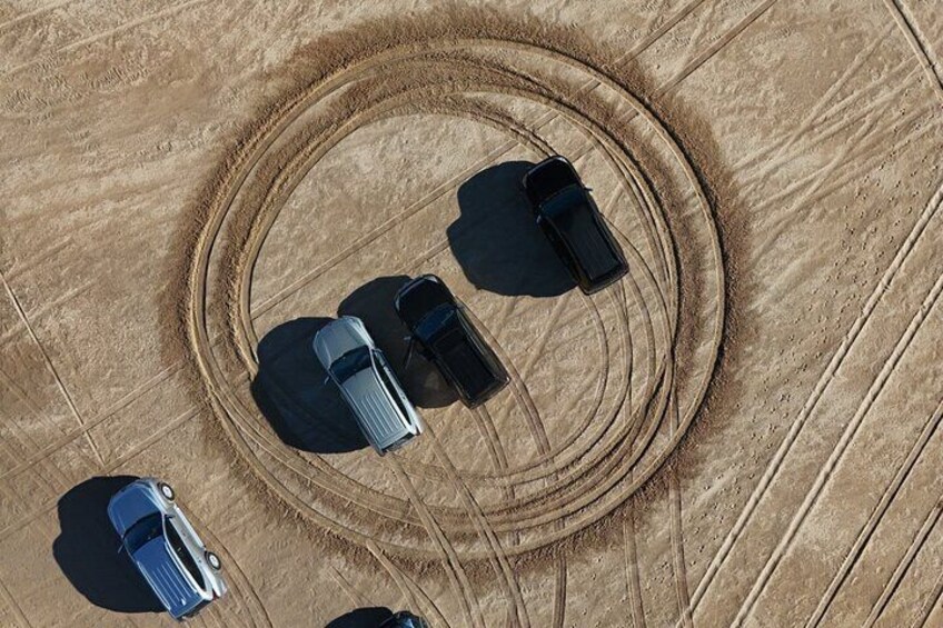 An aerial view of a circular track with four cars parked at the center. 4
