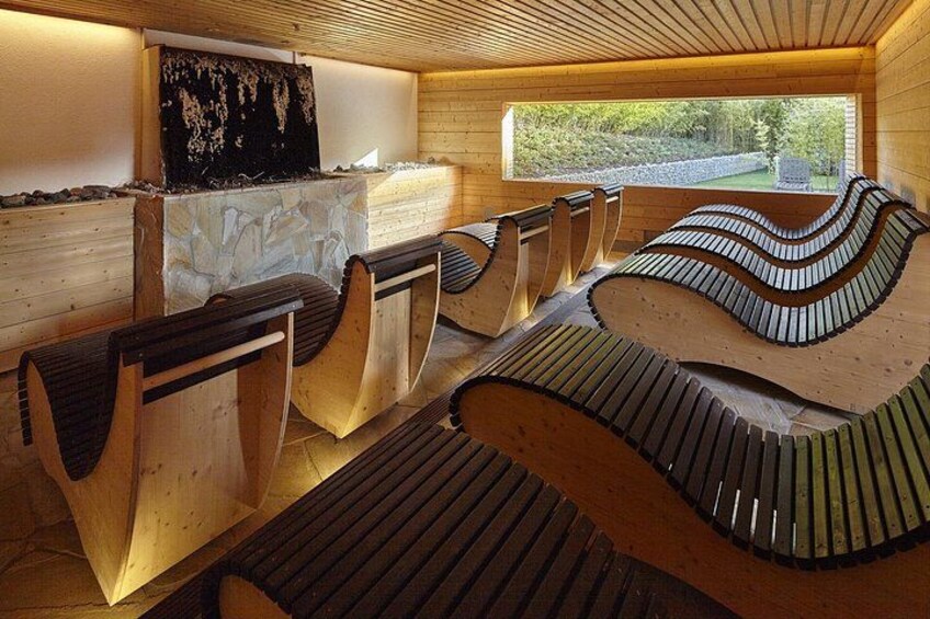 A wooden interior with curved benches and a stone wall. 5