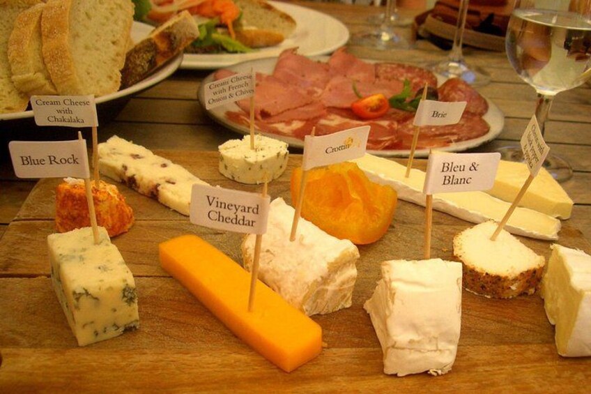 A variety of cheeses on a wooden table with labels. 2