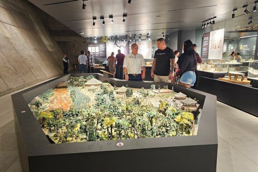 A museum exhibit with a large diorama of a landscape, including miniature buildings and vegetation. 1