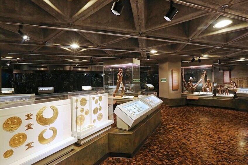 An indoor museum with display cases containing artifacts and a central exhibit with a seated figure. 1