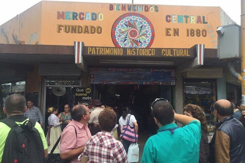 A crowded market entrance with a sign reading 'BENEVIDOS MERCADO FUNDADO EN 1880'. 5