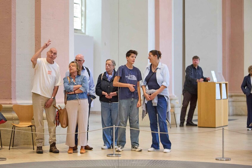 A group of people standing in a room with a podium and a rope barrier. 2