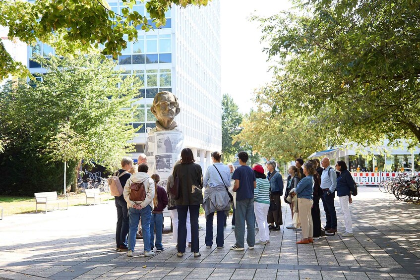 A group of people standing in a park with a statue in the background. 3
