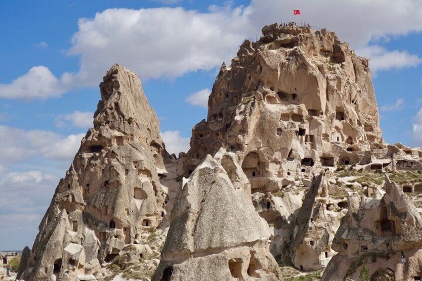 A rocky mountain with numerous caves and a flag on top. 4