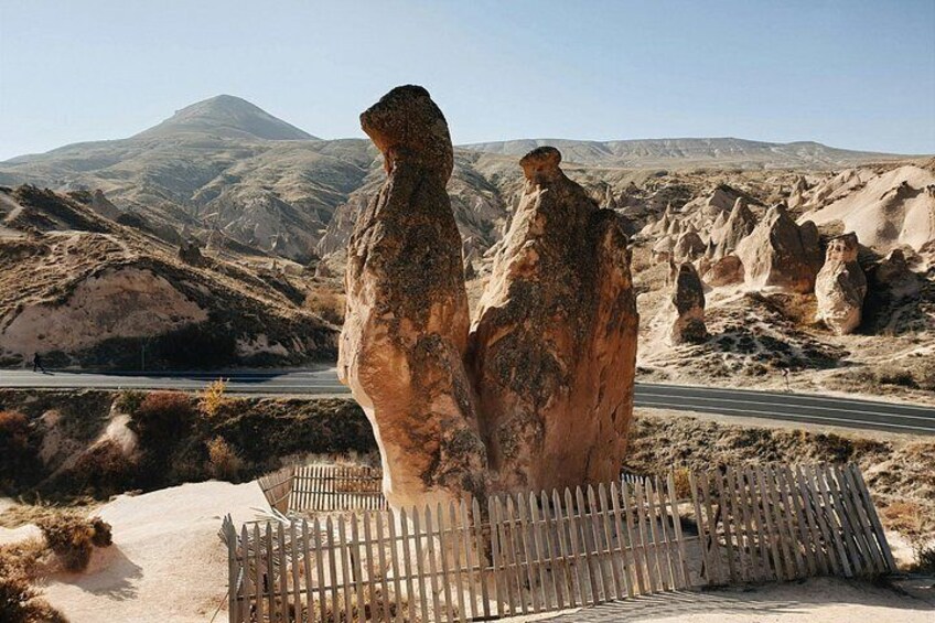 A desert landscape with rock formations, a road, and a mountain in the background. 3