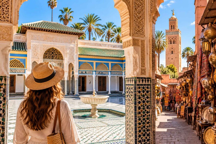 A woman in a hat walking through a courtyard with intricate tile work, palm trees, and a fountain. 1