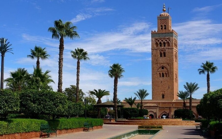 A tall tower with intricate designs, surrounded by palm trees and greenery. 5
