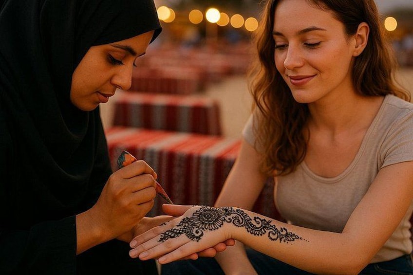 Two people applying henna on one person's arm. 2
