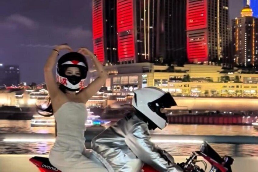 A person on a motorcycle wearing a helmet, with a cityscape in the background. 3