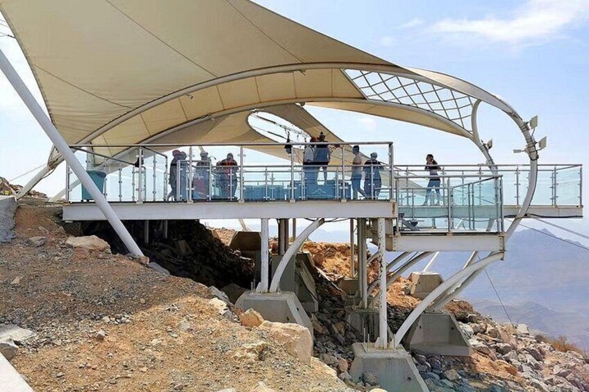 Un puente peatonal con techo que domina un terreno rocoso y una masa de agua. 3