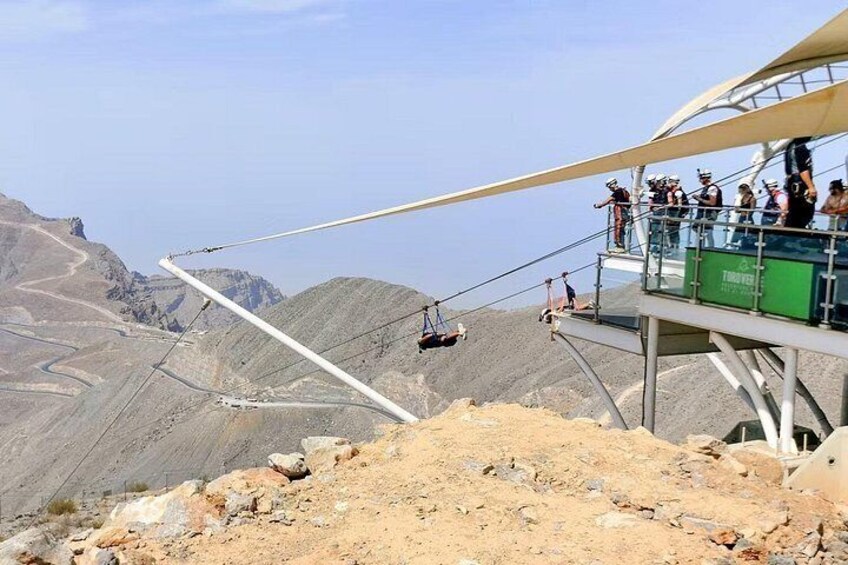 Un sistema de teleférico con pasajeros, un paisaje montañoso y un cielo despejado. 2