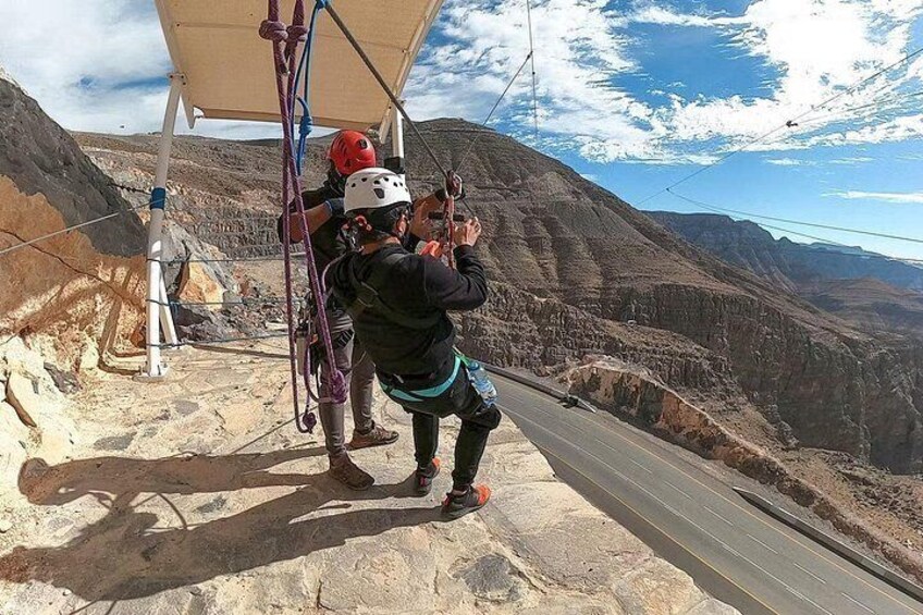 Una persona haciendo rappel por una montaña con arnés y casco, con un paisaje rocoso y cielo despejado al fondo. 4