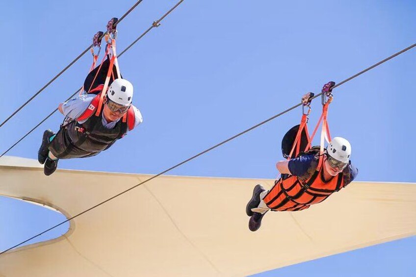 Twee mensen ziplinen met veiligheidsgordels en helmen. 2