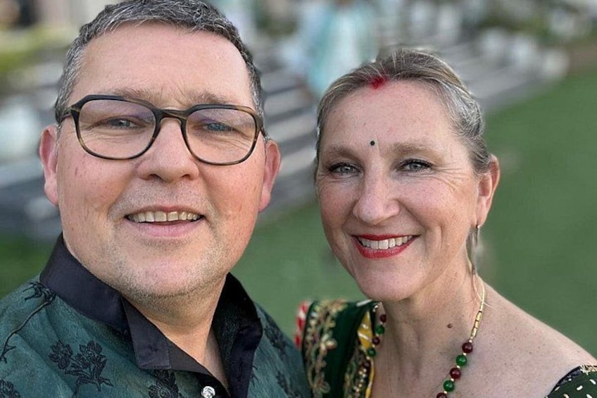 A person wearing a green patterned shirt and another in a green and gold traditional outfit. 1