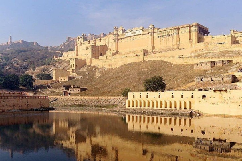 A historic fort with a reflection in the water, a hilly landscape, and a clear sky. 2