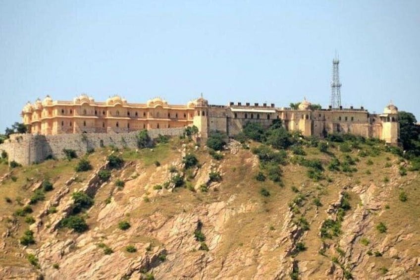 A large, historic building with multiple domes and towers, situated on a rocky hill with sparse vegetation. 5