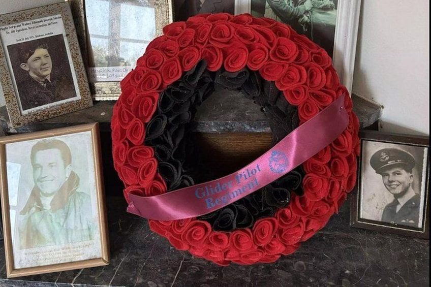 A wreath with red and black roses, a ribbon, and framed photographs. 5