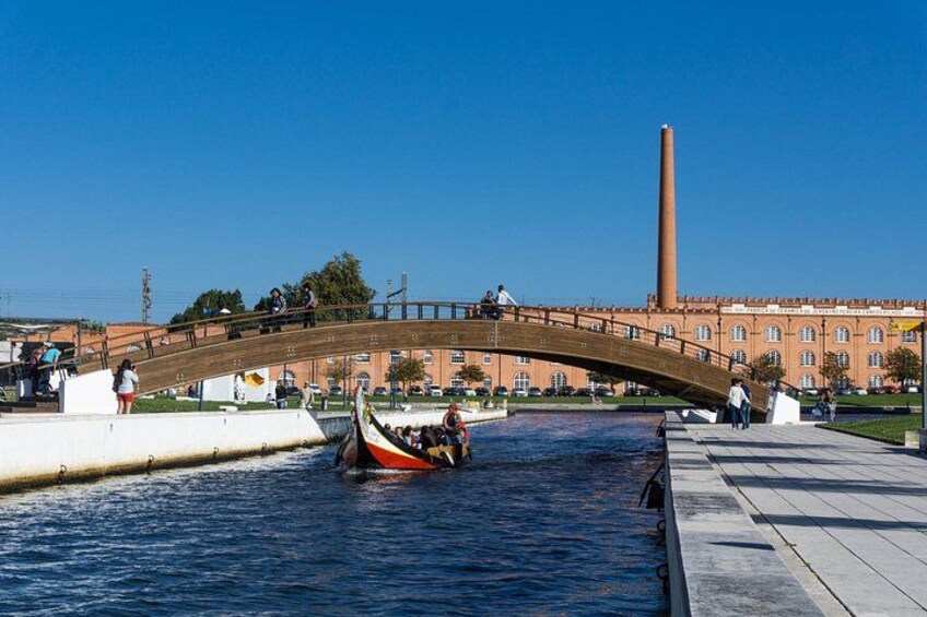 A gondola on a canal, a bridge, and a tall chimney in the background. 2