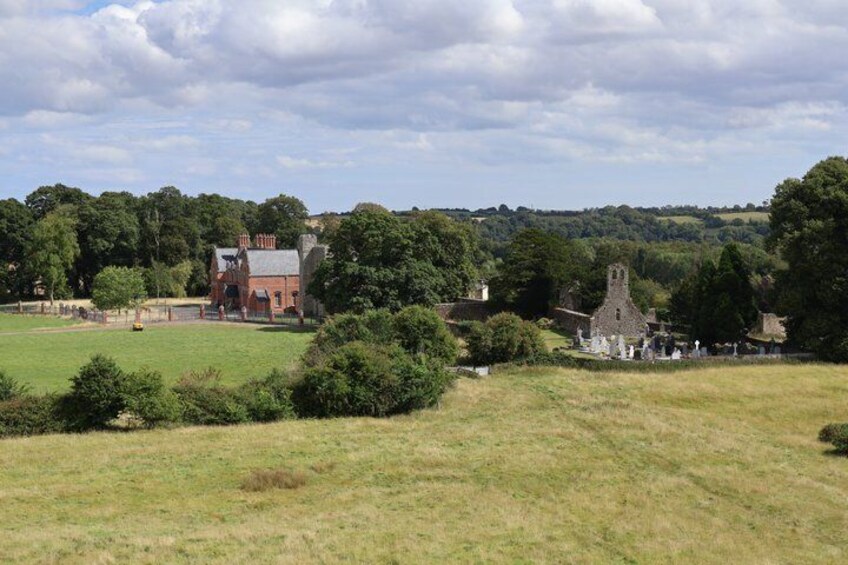 A rural landscape with a church, a red brick building, and a cemetery. 4
