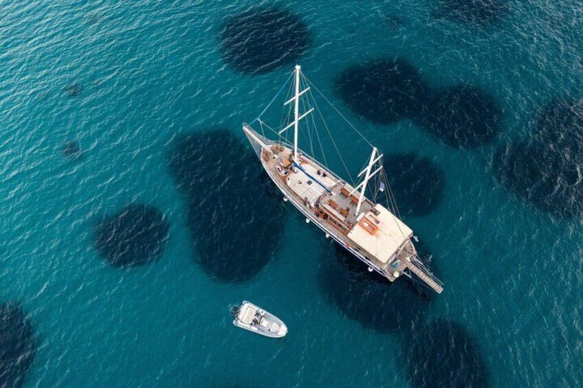 A sailboat anchored near a rocky outcrop in clear blue waters. 5