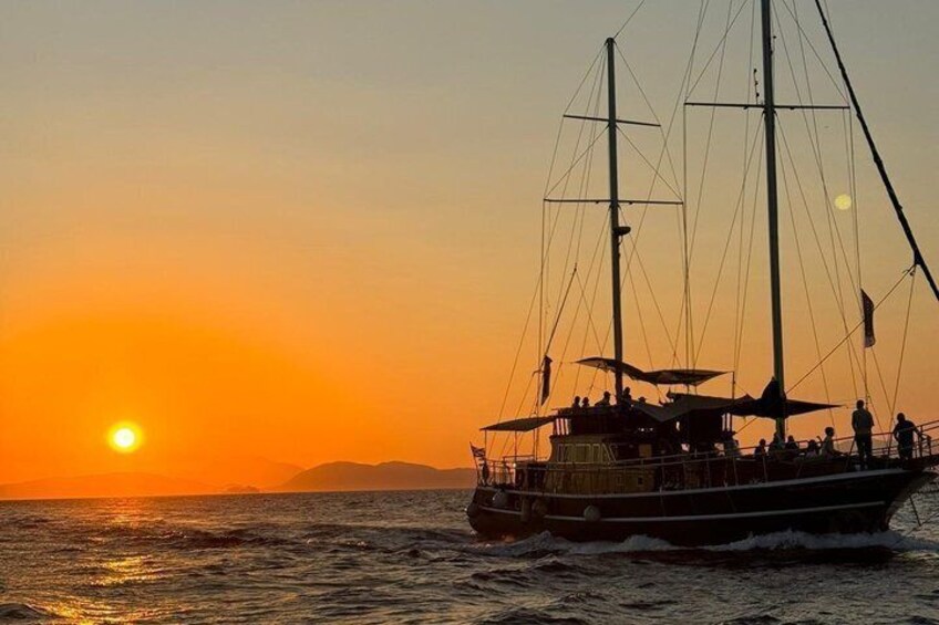 A sailing boat with multiple masts and passengers, sailing on the ocean during sunset. 4