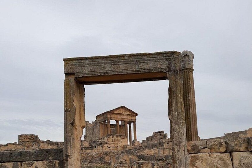 Ancient ruins with a central structure featuring columns and a triangular pediment. 4