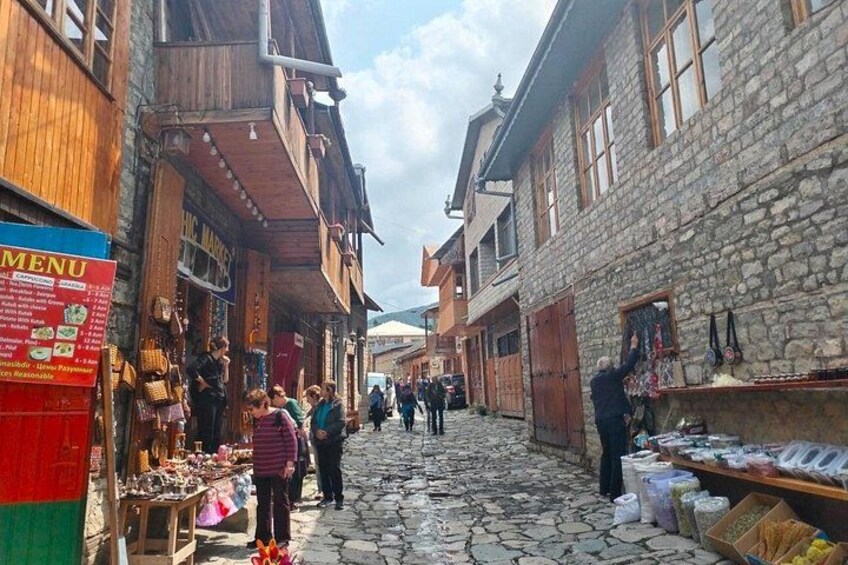 A cobblestone street with shops and people. 4