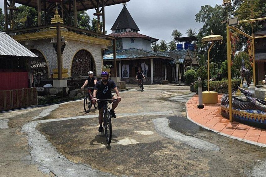 Ein Tempel mit einer großen goldenen Statue, einer Drachenverziierung und einer Person, die Fahrrad fährt. 3