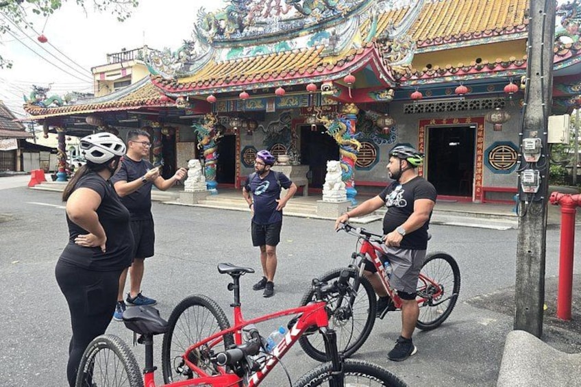 Ein Tempel mit aufwendiger Architektur, ein rotes Fahrrad und zwei Personen mit Helmen. 4