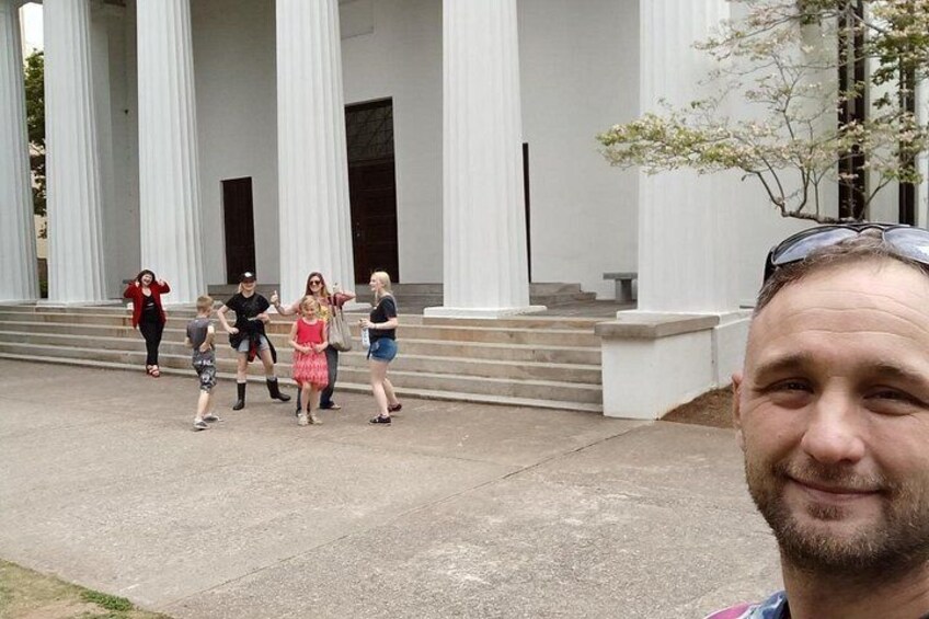 A group of people walking in front of a building with large columns. 1