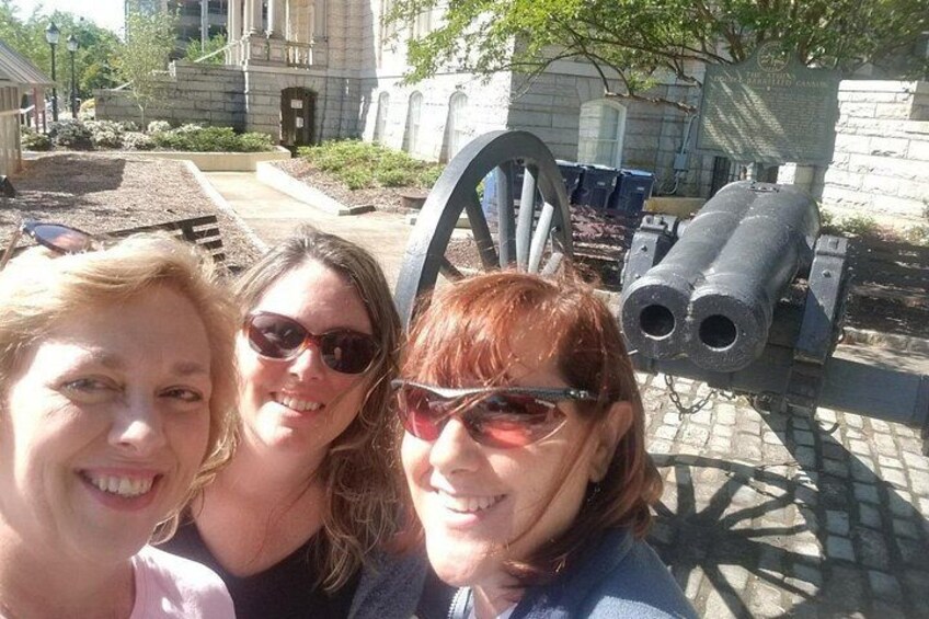 Three people in front of a cannon and a building. 2