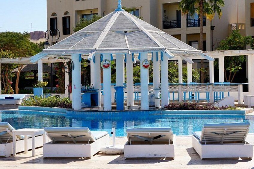 A pool with lounge chairs, a gazebo, and a building in the background. 5