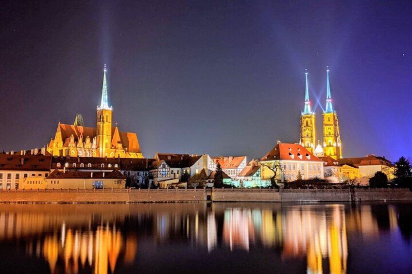 Une vue nocturne d’une ville, avec des bâtiments illuminés et une rivière reflétant les lumières. 1