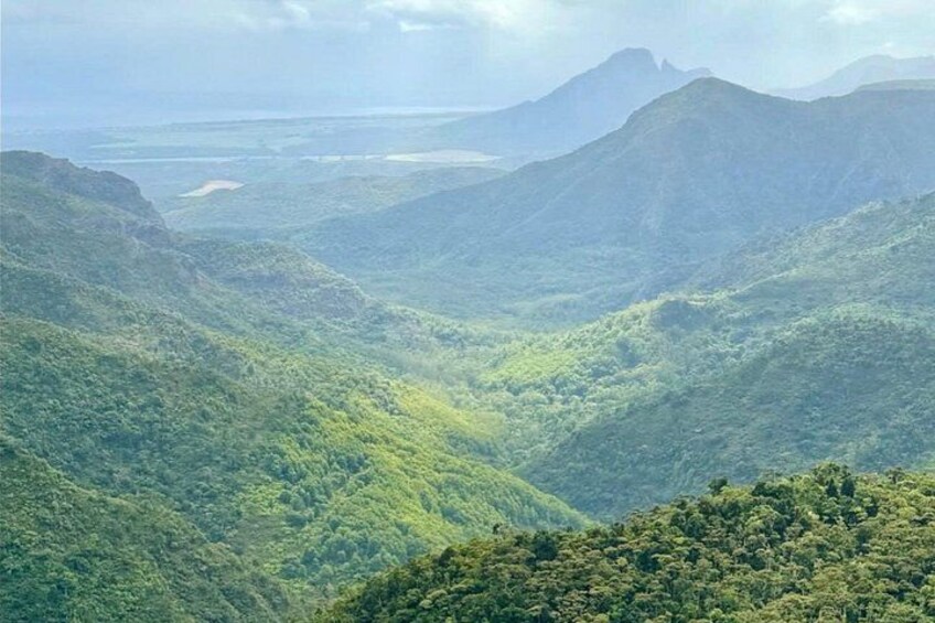 A mountainous landscape with dense green forests and a valley. 2