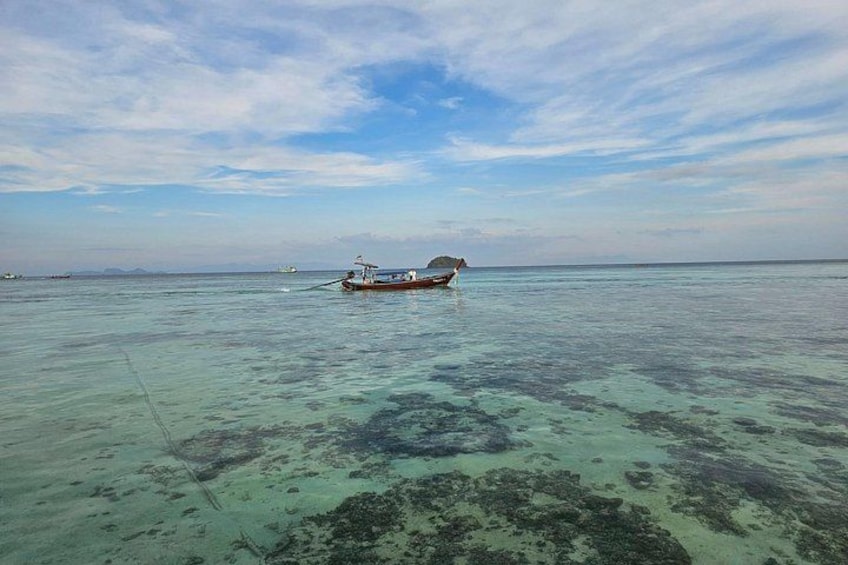 A boat on clear turquoise water with a distant island and a clear sky. 2