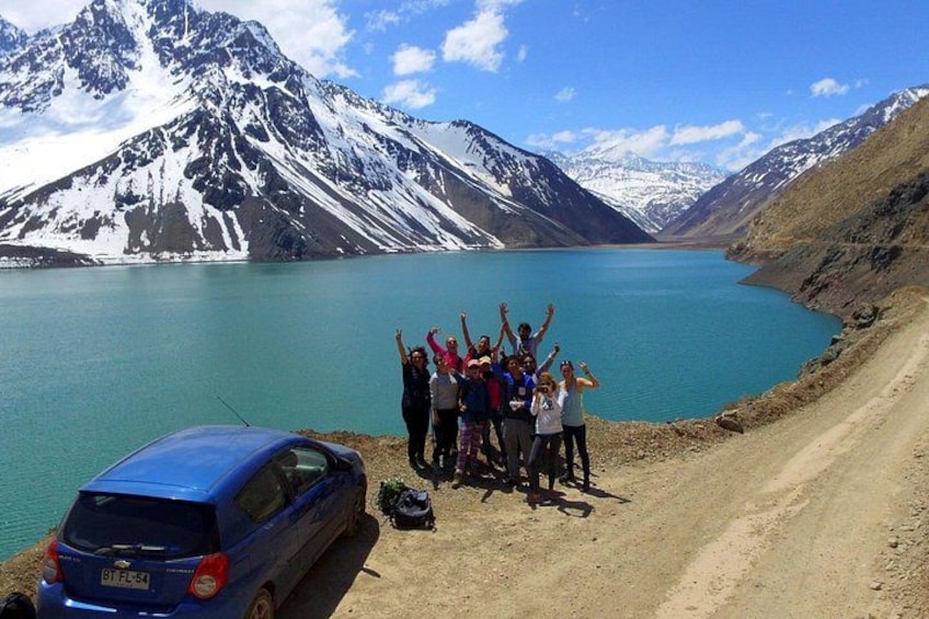 A group of people by a lake with mountains in the background. 2