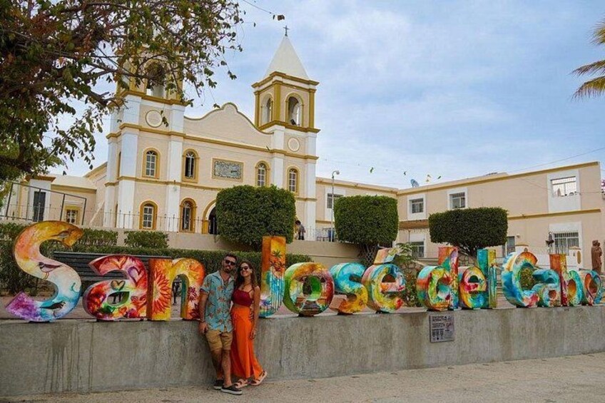 A colorful street sign with the name 'Santiago de Compostela' and a church in the background. 3