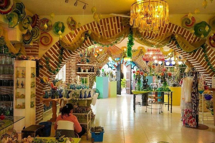 A brightly lit store with colorful glassware, a chandelier, and a brick wall. 4