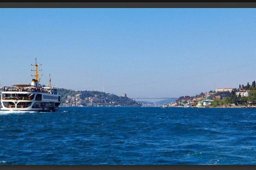 A ferry on a blue sea with a cityscape in the background. 2