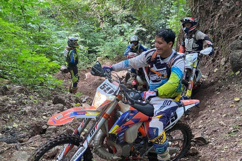 A person on a dirt bike in a forested area. 1