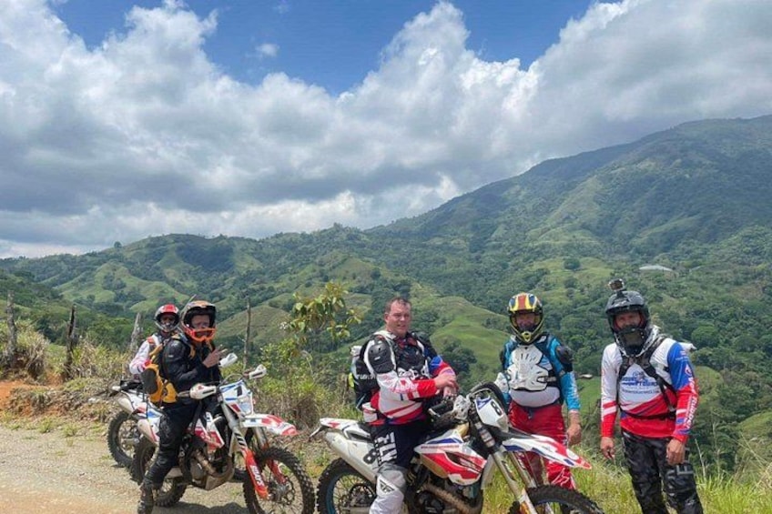 A group of motorcyclists on a dirt road with a mountainous landscape in the background. 4