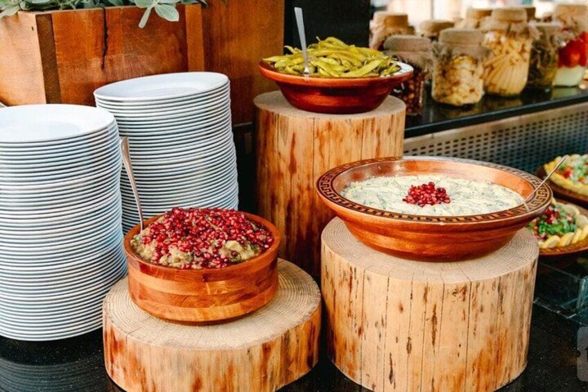 Wooden bowls on tree stumps with food, surrounded by stacked plates. 2