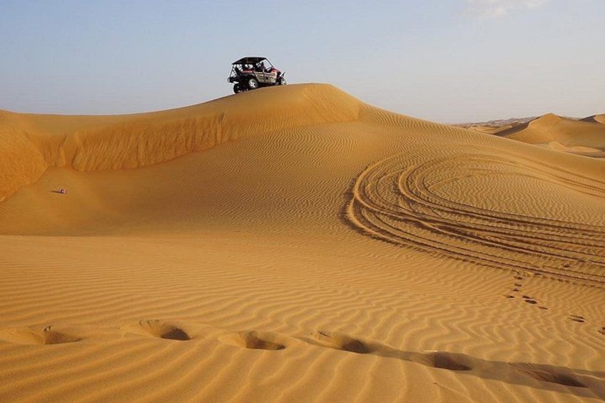 A vehicle on a sand dune with tire tracks. 3