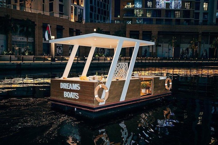 A wooden boat named 'Dreams Boats' with a canopy, life rings, and a sign on the side. 1