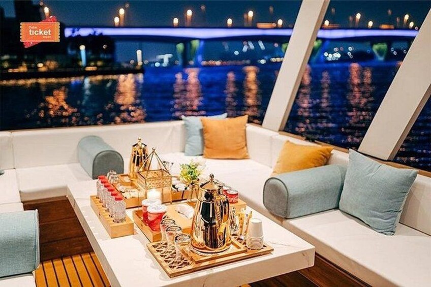 A luxurious seating area with a table set for a meal, overlooking a cityscape with a bridge. 5