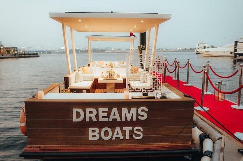 A boat named 'DREAMS BOATS' with a covered seating area and a red carpet. 4