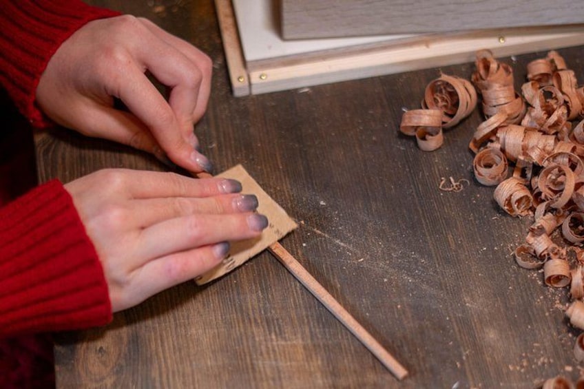 Manos armando un objeto de madera con un palito. 2