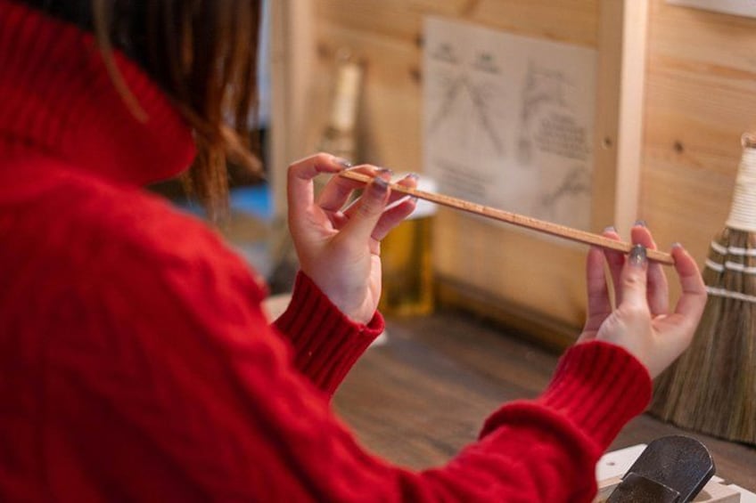 A person in a red sweater holding a wooden stick. 2