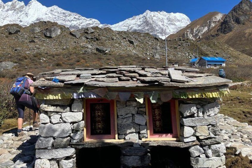 A stone structure with a red door, a person with a backpack, and snow-capped mountains in the background. 5